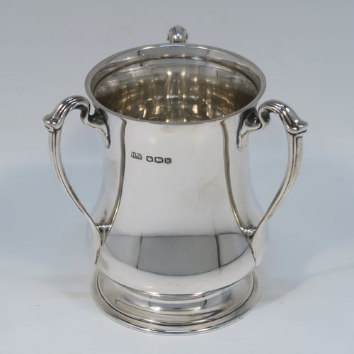 An unusual and very handsome Sterling Silver Tyg-style christening mug, having a plain round bellied body, with three scroll side-handles, and sitting on a pedestal foot. This elegant silver Tyg mug was made by the Atkins Brothers of Sheffield in 1927. The dimensions of this fine hand-made silver christening  mug are height 9 cms (3.5 inches), diameter at top 6.5 cms (2.5 inches), and it weighs approx. 191g (6.2 troy ounces).   