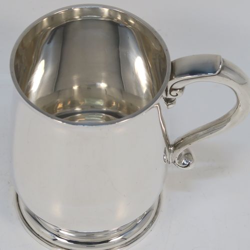 A very handsome Antique Sterling Silver half-pint tankard style christening mug, having a plain round bellied body, a scroll handle with thumb-piece, and sitting on a pedestal foot. This elegant antique silver mug was made by Holland, Aldwinkle, and Slater of London in 1912. The dimensions of this fine hand-made antique silver christening mug tankard are height 10 cms (4 inches), diameter at top 7 cms (2.75 inches), and it weighs approx. 240g (7.7 troy ounces).   