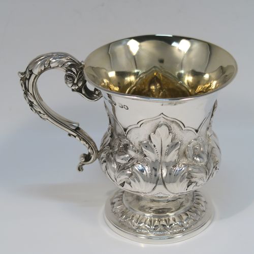 A beautiful Antique Georgian Sterling Silver christening mug, having a round bellied body, with hand-chased floral and leaf style decoration, an acanthus leaf scroll handle, a gold-gilt interior, and sitting on a pedestal foot. This fantastic silver christening mug was made by Charles Fox of London in 1829. The dimensions of this fine hand-made antique silver christening mug are height 9.5 cms (3.75 inches), length 11.5 cms (4.5 inches), and it weighs approx. 142g (4.6 troy ounces).   