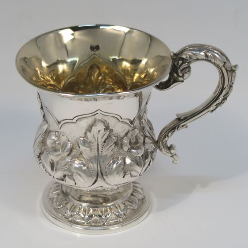 A beautiful Antique Georgian Sterling Silver christening mug, having a round bellied body, with hand-chased floral and leaf style decoration, an acanthus leaf scroll handle, a gold-gilt interior, and sitting on a pedestal foot. This fantastic silver christening mug was made by Charles Fox of London in 1829. The dimensions of this fine hand-made antique silver christening mug are height 9.5 cms (3.75 inches), length 11.5 cms (4.5 inches), and it weighs approx. 142g (4.6 troy ounces).   