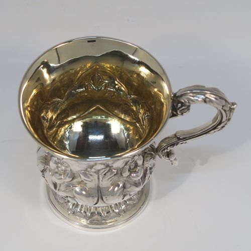 A beautiful Antique Georgian Sterling Silver christening mug, having a round bellied body, with hand-chased floral and leaf style decoration, an acanthus leaf scroll handle, a gold-gilt interior, and sitting on a pedestal foot. This fantastic silver christening mug was made by Charles Fox of London in 1829. The dimensions of this fine hand-made antique silver christening mug are height 9.5 cms (3.75 inches), length 11.5 cms (4.5 inches), and it weighs approx. 142g (4.6 troy ounces).   
