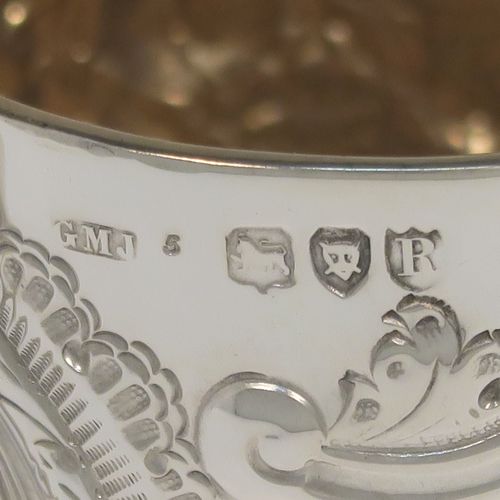 A very pretty Antique Victorian Sterling Silver christening mug, having a round straight-sided body with tucked under belly, all hand-chased with floral, scroll-work, and fluted decoration, a central vacant cartouche, a plain scroll handle, a gold-gilt interior, and all sitting on a collet foot. This beautiful silver mug was made by George Maudsley Jackson of London in 1893. The dimensions of this fine hand-made antique silver christening mug 6.5re height 9.5 cms (3.75 inches), diameter at lip 7 cms (2.6 inches), and it weighs approx. 146g (4.7 troy ounces).   