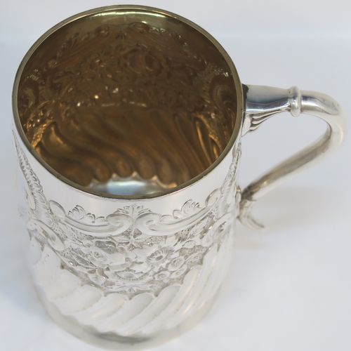A very pretty Antique Victorian Sterling Silver christening mug, having a round straight-sided body with tucked under belly, all hand-chased with floral, scroll-work, and fluted decoration, a central vacant cartouche, a plain scroll handle, a gold-gilt interior, and all sitting on a collet foot. This beautiful silver mug was made by George Maudsley Jackson of London in 1893. The dimensions of this fine hand-made antique silver christening mug 6.5re height 9.5 cms (3.75 inches), diameter at lip 7 cms (2.6 inches), and it weighs approx. 146g (4.7 troy ounces).   
