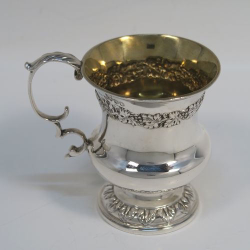 A very handsome Antique Georgian Sterling Silver christening mug, having a round bellied Campagna style body, with an upper band of hand-chased grapevine work, a gold-gilt interior, an acanthus leaf scroll handle, and sitting on a pedestal foot. This elegant antique silver christening mug was made by Joseph Angell II of London in 1824. The dimensions of this fine hand-made antique silver christening mug are height 8.5 cms (3.3 inches), length 9 cms (3.5 inches), and it weighs approx. 121g (3.9 troy ounces).   
