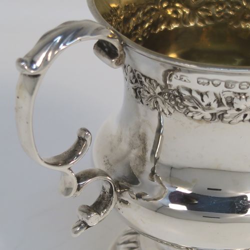 A very handsome Antique Georgian Sterling Silver christening mug, having a round bellied Campagna style body, with an upper band of hand-chased grapevine work, a gold-gilt interior, an acanthus leaf scroll handle, and sitting on a pedestal foot. This elegant antique silver christening mug was made by Joseph Angell II of London in 1824. The dimensions of this fine hand-made antique silver christening mug are height 8.5 cms (3.3 inches), length 9 cms (3.5 inches), and it weighs approx. 121g (3.9 troy ounces).