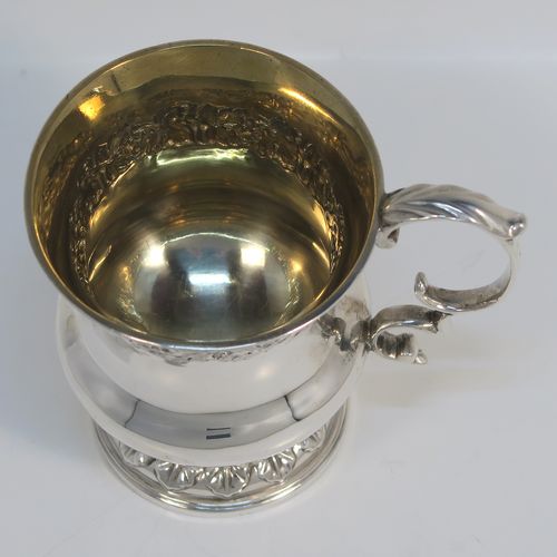 A very handsome Antique Georgian Sterling Silver christening mug, having a round bellied Campagna style body, with an upper band of hand-chased grapevine work, a gold-gilt interior, an acanthus leaf scroll handle, and sitting on a pedestal foot. This elegant antique silver christening mug was made by Joseph Angell II of London in 1824. The dimensions of this fine hand-made antique silver christening mug are height 8.5 cms (3.3 inches), length 9 cms (3.5 inches), and it weighs approx. 121g (3.9 troy ounces).