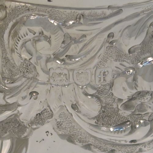 A very pretty Antique Victorian Sterling Silver christening mug, having a round tapering sides, all hand-chased with floral, scroll-work, and fluted decoration, a cast and bead-edged scroll handle, a central vacant cartouche opposite the handle, a gold-gilt interior, and all sitting on a pedestal foot. This beautiful silver christening mug was made by Wakely and Wheeler of London in 1901. The dimensions of this fine hand-made antique silver christening mug are height 9.5 cms (3.75 inches), diameter at lip 7.5 cms (3 inches), and it weighs approx. 161g (5.2 troy ounces).  