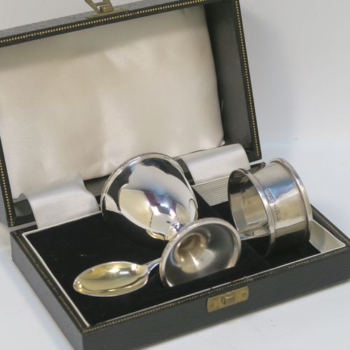 A handsome Sterling Silver three-piece christening set, consisting of a plain round napkin ring, a plain round egg cup with applied floral and scroll borders and a gold-gilt interior, and a plain Hanoverian pattern spoon with a gold-gilt bowl, all in their original cream satin and black velvet-lined presentation box. This elegant christening set was made by Turner and Simpson Birmingham in 1960 (the napkin ring was made by Henry Matthews of Birmingham in 1935). The dimensions of this fine hand-made silver christening set are length of spoon 10 cms (4 inches), diameter of napkin ring 4.5 cms (1.75 inches), height of egg cup 6.5 cms (2.75 inches), and the total weight is approx. 56g (1.8 troy ounces).   