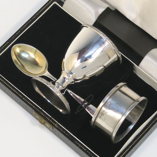 A handsome Sterling Silver three-piece christening set, consisting of a plain round napkin ring, a plain round egg cup with applied floral and scroll borders and a gold-gilt interior, and a plain Hanoverian pattern spoon with a gold-gilt bowl, all in their original cream satin and black velvet-lined presentation box. This elegant christening set was made by Turner and Simpson Birmingham in 1960 (the napkin ring was made by Henry Matthews of Birmingham in 1935). The dimensions of this fine hand-made silver christening set are length of spoon 10 cms (4 inches), diameter of napkin ring 4.5 cms (1.75 inches), height of egg cup 6.5 cms (2.75 inches), and the total weight is approx. 56g (1.8 troy ounces).