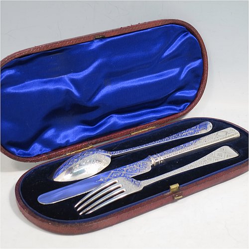 An Antique Victorian Sterling Silver christening set, having a knife, fork, and spoon, all hand-engraved with geometrical and floral work, and all sitting in their original dark blue satin and velvet-lined presentation box. Made by George Adams of London in 1871. The dimensions of this fine hand-made antique silver christening set are length of knife 19 cms (7.5 inches), with a total weight of approx. 100g (3 troy ounces).    