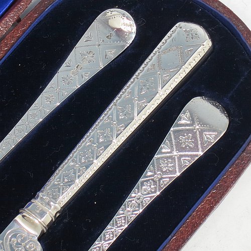 An Antique Victorian Sterling Silver christening set, having a knife, fork, and spoon, all hand-engraved with geometrical and floral work, and all sitting in their original dark blue satin and velvet-lined presentation box. Made by George Adams of London in 1871. The dimensions of this fine hand-made antique silver christening set are length of knife 19 cms (7.5 inches), with a total weight of approx. 100g (3 troy ounces).
