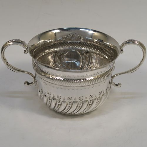A pretty Antique Edwardian Sterling Silver christening set, consisting of a two-handled porringer with hand-chased fluted decoration, together with a serving spoon, all in their blue satin and velvet-lined presentation box. The porringer was made by Henry Stratford of London in 1908, whilst the spoon was made by Thomas Bradbury of London in 1897. The dimensions of this fine hand-made silver christening set are length of spoon 14 cms (5.5 inches), diameter of bowl 10 cms (4 inches), and the total weight is approx. 172g (5.5 troy ounces).