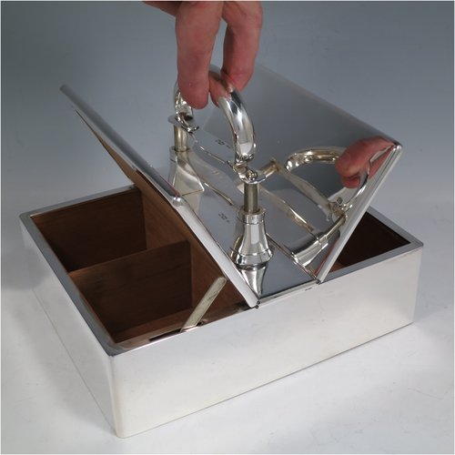 A Sterling Silver partners table cigar box, having a large plain rectangular body, with double hinged compartments opened by a mechanical carrying handle, and cedar wood-lined interiors. Made in London in 1933. The dimensions of this fine hand-made silver table cigar box are length 21 cms (8.25 inches), width 17 cms (6.75 inches), height inc. handle 14 cms (5.5 inches).