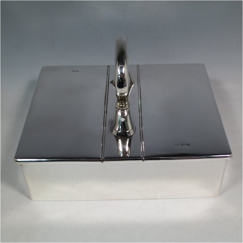 A Sterling Silver partners table cigar box, having a large plain rectangular body, with double hinged compartments opened by a mechanical carrying handle, and cedar wood-lined interiors. Made in London in 1933. The dimensions of this fine hand-made silver table cigar box are length 21 cms (8.25 inches), width 17 cms (6.75 inches), height inc. handle 14 cms (5.5 inches).