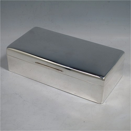A Sterling Silver cigarette or cigar table box, having a plain rectangular body with nice rounded corners, a hinged lid having an applied thumb-piece, a gold-gilt interior to the lid, and a cedar wood-lined interior to the base, with a removable divider. Made by Alexander Clarke of London in 1925. The dimensions of this fine hand-made silver table box are length 17.5 cms (7 inches), width 9 cms (3.5 inches), and height 5 cms (2 inches).
