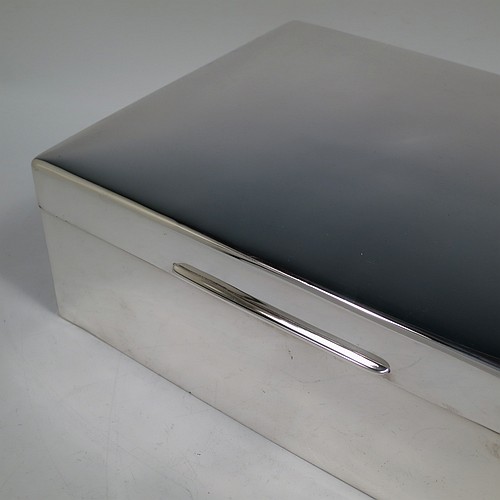 A very large Sterling Silver cigarette or cigar humidor table box, having a plain rectangular body with nice rounded corners, a hinged lid having an applied thumb-piece, a cedar wood-lined interior to lid and base, with two removable dividers. Made in London in 1923. The dimensions of this fine hand-made silver table box are length 30.5 cms (12 inches), width 23 cms (9 inches), and height 10 cms (4 inches).