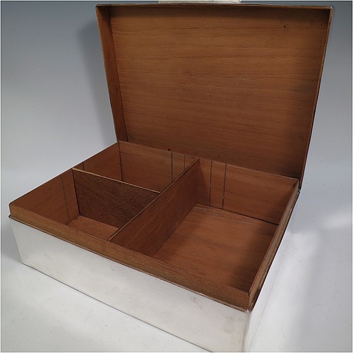 A very large Sterling Silver cigarette or cigar humidor table box, having a plain rectangular body with nice rounded corners, a hinged lid having an applied thumb-piece, a cedar wood-lined interior to lid and base, with two removable dividers. Made in London in 1923. The dimensions of this fine hand-made silver table box are length 30.5 cms (12 inches), width 23 cms (9 inches), and height 10 cms (4 inches).