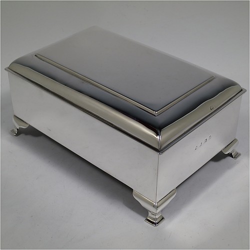 A large and very stylish Antique Edwardian Sterling Silver cigar / cigarette box, having a plain rectangular body, with a stepped and flat-topped hinged lid, a cedar wood-lined interior with internal divider, and all sitting on four cast stepped feet. Made by A. & J. Zimmerman of Birmingham in 1903. The dimensions of this fine hand-made antique silver table box are length 20 cms (8 inches), width 13.5 cms (5.25 inches), and height 9 cms (3.5 inches).