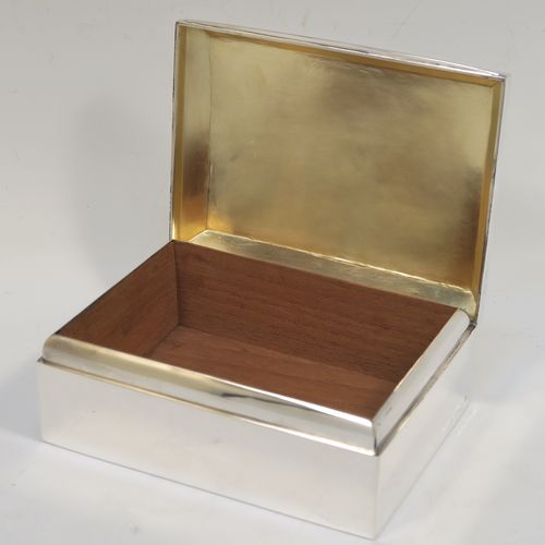 A very elegant Antique Sterling Silver cigarette / cigar table box, having a plain rectangular body, a hinged lid having an applied thumb-piece and chamfered edges, with a gold-gilt and cedar wood-lined interior to the base. This handsome antique silver table box was made by A. and J. Zimmerman of Birmingham in 1912. The dimensions of this fine hand-made antique silver table cigar or cigarette box are length 13.5 cms (5.3 inches), width 10 cms (4 inches), and height 5.5 cms (2.25 inches).