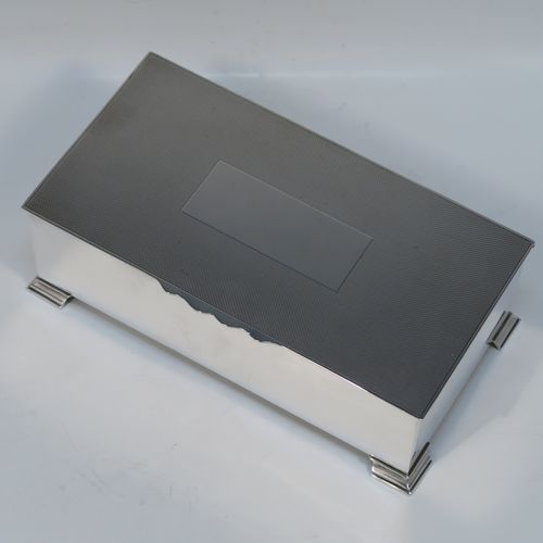A very elegant Sterling Silver Art Deco style cigarette / cigar table box, having a very plain rectangular body with straight sides, a hinged lid with engine-turned decoration, a central vacant cartouche and thumb-piece, a wooden cedar-lined interior with two dividers, and all sitting on four stepped corner feet. This handsome silver table box was made by Mappin & Webb of London in 1947. The dimensions of this fine hand-made Art Deco silver table box are length 18 cms (7 inches), height 6 cms (2.5 inches), and width 9.5 cms (3.75 inches).