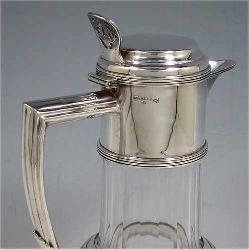 An Antique Victorian Silver Plated and hand-cut crystal claret jug, having a plain round mount with applied reeded borders, a stepped lid with a hand-pierced thumb-piece, a flat-topped scroll handle attached to a round and reeded security ring, together with a hand-cut round, panelled, and bellied crystal body with star-cut base. Made by William Hutton and Sons of Sheffield in 1880. The dimensions of this fine hand-made antique silver plated and crystal claret jug are height 24 cms (9.5 inches), and length 15 cms (6 inches).