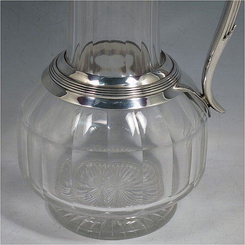 An Antique Victorian Silver Plated and hand-cut crystal claret jug, having a plain round mount with applied reeded borders, a stepped lid with a hand-pierced thumb-piece, a flat-topped scroll handle attached to a round and reeded security ring, together with a hand-cut round, panelled, and bellied crystal body with star-cut base. Made by William Hutton and Sons of Sheffield in 1880. The dimensions of this fine hand-made antique silver plated and crystal claret jug are height 24 cms (9.5 inches), and length 15 cms (6 inches).