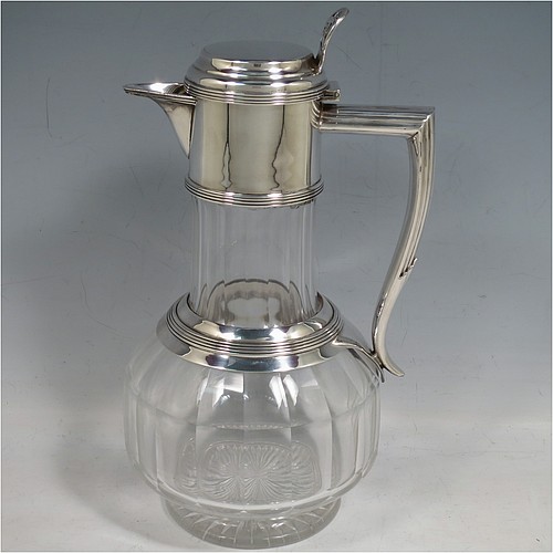 An Antique Victorian Silver Plated and hand-cut crystal claret jug, having a plain round mount with applied reeded borders, a stepped lid with a hand-pierced thumb-piece, a flat-topped scroll handle attached to a round and reeded security ring, together with a hand-cut round, panelled, and bellied crystal body with star-cut base. Made by William Hutton and Sons of Sheffield in 1880. The dimensions of this fine hand-made antique silver plated and crystal claret jug are height 24 cms (9.5 inches), and length 15 cms (6 inches).