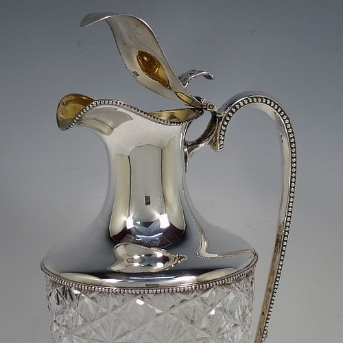 A very beautiful Antique Edwardian Sterling Silver and hand-cut crystal claret jug, having a round vase-shaped body with a plain round mount and applied bead-edged borders, a hinged lid with a hand-pierced thumb-piece over a spout with gold-gilt interior, a beaded and scroll side-handle, a hand-cut hobnail and star pattern main body, and all sitting on a round and stepped pedestal foot. Made by Walter and Charles Sissons of Sheffield in 1905. The dimensions of this fine hand-made antique silver and crystal claret jug are height 29 cms (11.5 inches), and length 13.5 cms (5.3 inches).