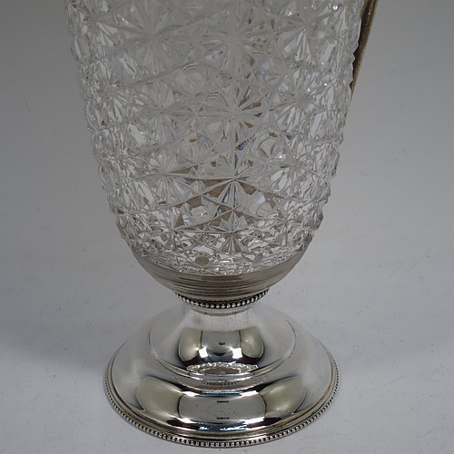 A very beautiful Antique Edwardian Sterling Silver and hand-cut crystal claret jug, having a round vase-shaped body with a plain round mount and applied bead-edged borders, a hinged lid with a hand-pierced thumb-piece over a spout with gold-gilt interior, a beaded and scroll side-handle, a hand-cut hobnail and star pattern main body, and all sitting on a round and stepped pedestal foot. Made by Walter and Charles Sissons of Sheffield in 1905. The dimensions of this fine hand-made antique silver and crystal claret jug are height 29 cms (11.5 inches), and length 13.5 cms (5.3 inches).
