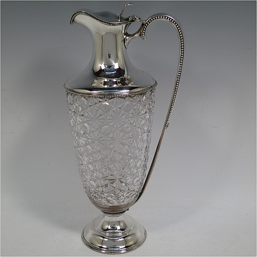 A very beautiful Antique Edwardian Sterling Silver and hand-cut crystal claret jug, having a round vase-shaped body with a plain round mount and applied bead-edged borders, a hinged lid with a hand-pierced thumb-piece over a spout with gold-gilt interior, a beaded and scroll side-handle, a hand-cut hobnail and star pattern main body, and all sitting on a round and stepped pedestal foot. Made by Walter and Charles Sissons of Sheffield in 1905. The dimensions of this fine hand-made antique silver and crystal claret jug are height 29 cms (11.5 inches), and length 13.5 cms (5.3 inches).