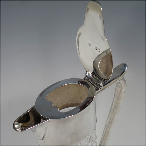 A very handsome Antique Victorian Sterling Silver and hand-cut crystal claret jug, having a plain oval mount, a hinged flat lid with scroll finial, a plain scroll handle with thumb-piece, together with a hand-cut Hobnail pattern oval body with straight tapering sides, and with a star-cut flat base. Made by William Hutton and Sons of London in 1900. The dimensions of this fine hand-made antique silver and crystal claret jug are height 27 cms (10.75 inches), and length 16.5 cms (6.5 inches).
