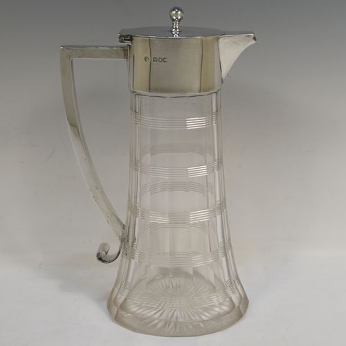 A very handsome Antique Victorian Sterling Silver and hand-cut crystal claret jug, having a plain oval mount, a hinged flat lid with a ball finial, a plain handle with scroll end, together with a hand-cut oval and panelled crystal body with reeded bands and star-cut base. This beautiful silver and crystal claret jug was made by William Hutton of London in 1900. The dimensions of this fine hand-made silver and crystal claret jug are height 26 cms (10.25 inches), and length 16 cms (6.25 inches).   
