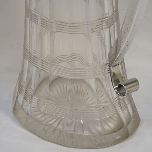 A very handsome Antique Victorian Sterling Silver and hand-cut crystal claret jug, having a plain oval mount, a hinged flat lid with a ball finial, a plain handle with scroll end, together with a hand-cut oval and panelled crystal body with reeded bands and star-cut base. This beautiful silver and crystal claret jug was made by William Hutton of London in 1900. The dimensions of this fine hand-made silver and crystal claret jug are height 26 cms (10.25 inches), and length 16 cms (6.25 inches).