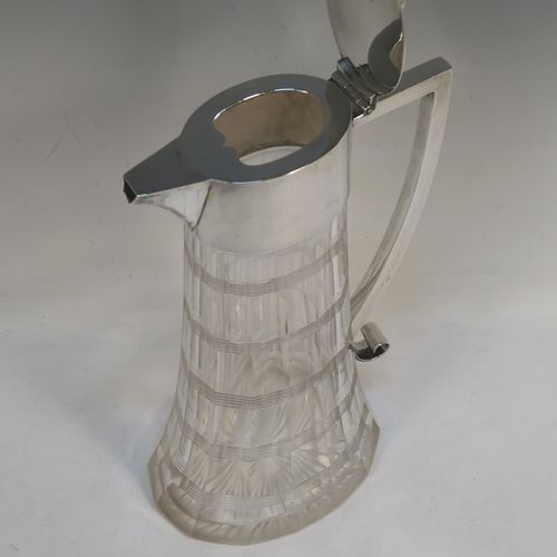 A very handsome Antique Victorian Sterling Silver and hand-cut crystal claret jug, having a plain oval mount, a hinged flat lid with a ball finial, a plain handle with scroll end, together with a hand-cut oval and panelled crystal body with reeded bands and star-cut base. This beautiful silver and crystal claret jug was made by William Hutton of London in 1900. The dimensions of this fine hand-made silver and crystal claret jug are height 26 cms (10.25 inches), and length 16 cms (6.25 inches).