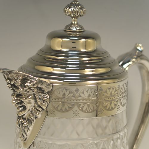 A very handsome and large Antique Victorian Silver Plated and hand-cut crystal claret jug, having a hand-engraved mount with floral decoration, a Bacchus face on the spout, a hinged stepped and domed lid with cast finial, a scroll side handle attached to a lower strengthening girdle, and a round hand-cut straight-sided body with a single band of hand-engraved frosted cut work in a grapevine pattern with two bands of hobnail pattern above and below, all sitting on a flat base with a star-cut. Made in ca.1880. The dimensions of this fine hand-made antique silver-plated and crystal claret jug are height 29 cms (11.5 inches), length 20 cms (8 inches), and diameter at the base is 13 cms (5 inches).