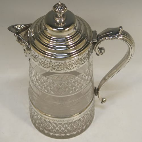 A very handsome and large Antique Victorian Silver Plated and hand-cut crystal claret jug, having a hand-engraved mount with floral decoration, a Bacchus face on the spout, a hinged stepped and domed lid with cast finial, a scroll side handle attached to a lower strengthening girdle, and a round hand-cut straight-sided body with a single band of hand-engraved frosted cut work in a grapevine pattern with two bands of hobnail pattern above and below, all sitting on a flat base with a star-cut. Made in ca.1880. The dimensions of this fine hand-made antique silver-plated and crystal claret jug are height 29 cms (11.5 inches), length 20 cms (8 inches), and diameter at the base is 13 cms (5 inches).