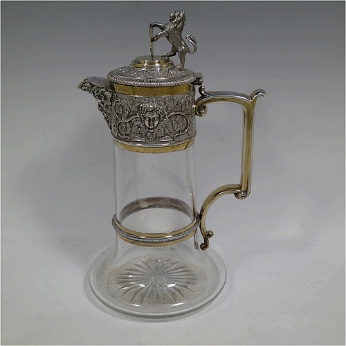 A very handsome Antique Victorian Silver Plated and hand-cut crystal claret jug, having an ornate parcel gilt Bacchus style round mount with hand-chased grapevine work, a sided handle with a bead-edged security ring, a hinged lid with a cast rampant lion and shield finial, together with a hand-cut crystal round body with straight sides and a tucked under belly above a flat star-cut base. Made by Elkington and Co., of Sheffield, with a date letter for 1883. The dimensions of this fine hand-made antique silver-plated and crystal claret jug are height 27 cms (10.5 inches), and length 16 cms (6.25 inches). Please note that this item is monogrammed on the finial shield.