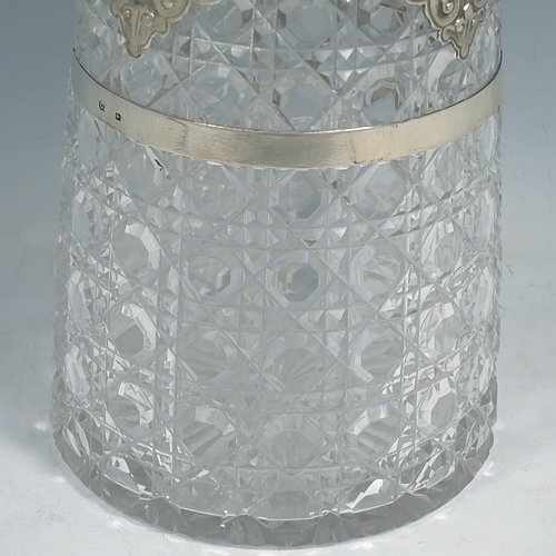 An Antique Victorian Sterling Silver and hand-cut crystal claret jug, having a hand-chased mount with floral decoration, oval vacant cartouches either side, a Bacchus face spout, a hinged lid with floral chasing and a cast finial, a cast scroll handle attached to a retaining ring, together with a hand-cut crystal body with hobnail-cut pattern. Made by Charles Boyton of London in 1882. The dimensions of this fine hand-made antique silver and crystal claret jug are height 29 cms (11.5 inches), and length 19 cms (7.5 inches).