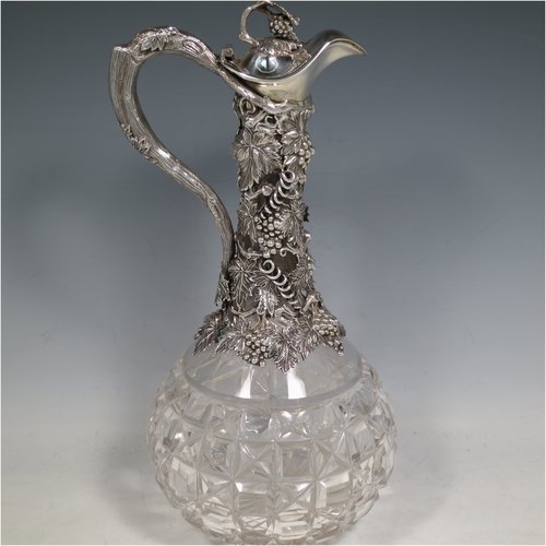 An Antique Victorian Sterling Silver and hand-cut crystal claret jug, having a cast grape and vine leaf mount on a hobnail-cut crystal round baluster body. with cast scroll vine tendril handle, a hinged lid with cast finial, and sitting on a flat star-cut base. Made by Cartwright & Woodward of Birmingham in 1860. The dimensions of this fine hand-made antique silver and crystal claret jug are height 31 cms (12.25 inches), and diameter at base 14 cms (5.5 inches).    