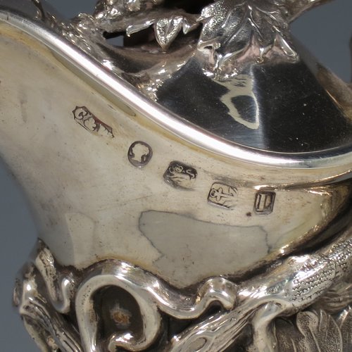 An Antique Victorian Sterling Silver and hand-cut crystal claret jug, having a cast grape and vine leaf mount on a hobnail-cut crystal round baluster body. with cast scroll vine tendril handle, a hinged lid with cast finial, and sitting on a flat star-cut base. Made by Cartwright & Woodward of Birmingham in 1860. The dimensions of this fine hand-made antique silver and crystal claret jug are height 31 cms (12.25 inches), and diameter at base 14 cms (5.5 inches).