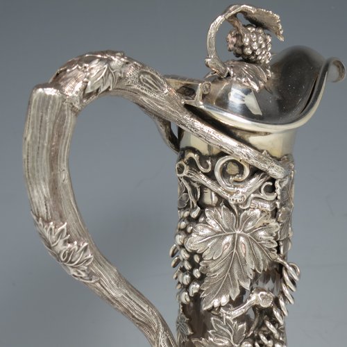 An Antique Victorian Sterling Silver and hand-cut crystal claret jug, having a cast grape and vine leaf mount on a hobnail-cut crystal round baluster body. with cast scroll vine tendril handle, a hinged lid with cast finial, and sitting on a flat star-cut base. Made by Cartwright & Woodward of Birmingham in 1860. The dimensions of this fine hand-made antique silver and crystal claret jug are height 31 cms (12.25 inches), and diameter at base 14 cms (5.5 inches).