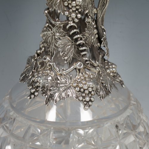 An Antique Victorian Sterling Silver and hand-cut crystal claret jug, having a cast grape and vine leaf mount on a hobnail-cut crystal round baluster body. with cast scroll vine tendril handle, a hinged lid with cast finial, and sitting on a flat star-cut base. Made by Cartwright & Woodward of Birmingham in 1860. The dimensions of this fine hand-made antique silver and crystal claret jug are height 31 cms (12.25 inches), and diameter at base 14 cms (5.5 inches).