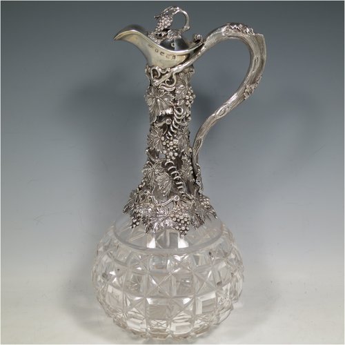 An Antique Victorian Sterling Silver and hand-cut crystal claret jug, having a cast grape and vine leaf mount on a hobnail-cut crystal round baluster body. with cast scroll vine tendril handle, a hinged lid with cast finial, and sitting on a flat star-cut base. Made by Cartwright & Woodward of Birmingham in 1860. The dimensions of this fine hand-made antique silver and crystal claret jug are height 31 cms (12.25 inches), and diameter at base 14 cms (5.5 inches).