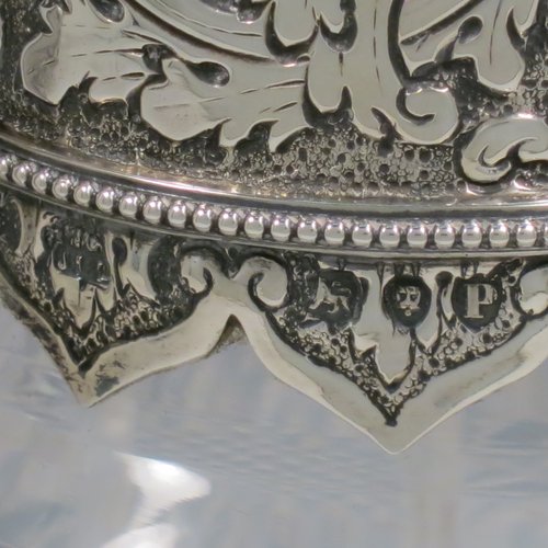 An Antique Victorian Sterling Silver and hand-cut crystal claret jug, having a hand-chased mount with floral decoration and a wavey bead-edged border, a hinged lid with cast floral finial, a hand-chased and engraved scroll handle attached to a hand-pierced floral band, together with an oval cross-section hand-cut Webb crystal body with star-cut panels, all sitting on a matching collet foot. Made by Gibson & Langland of London in 1890. The dimensions of this fine hand-made antique silver and crystal claret jug are height 31 cms (12.25 inches), and length 15 cms (6 inches).