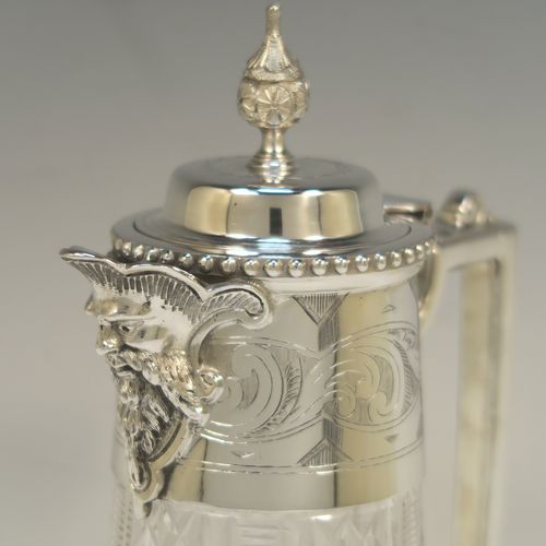 A very pretty Antique Victorian Silver Plated and hand-cut crystal claret jug, having a hand-engraved mount with scroll decoration, a Bacchus face on the spout, a hinged domed lid with a bead border and cast finial, a scrolled cast handle, a round hand-cut crystal body with tapering sides and a hobnail fluted panel pattern, all sitting on a flat star-cut base. Made by Mappin and Webb in there Princes Plate in ca. 1890. The dimensions of this fine hand-made antique silver-plated and crystal claret jug are height 28.5 cms (11.25 inches), length 14 cms (5.5 inches), and diameter at base is 11.5 cms (4.5 inches)..