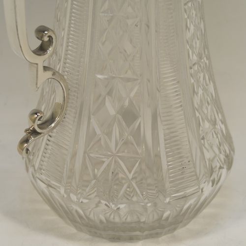 A very pretty Antique Victorian Silver Plated and hand-cut crystal claret jug, having a hand-engraved mount with scroll decoration, a Bacchus face on the spout, a hinged domed lid with a bead border and cast finial, a scrolled cast handle, a round hand-cut crystal body with tapering sides and a hobnail fluted panel pattern, all sitting on a flat star-cut base. Made by Mappin and Webb in there Princes Plate in ca. 1890. The dimensions of this fine hand-made antique silver-plated and crystal claret jug are height 28.5 cms (11.25 inches), length 14 cms (5.5 inches), and diameter at base is 11.5 cms (4.5 inches)..