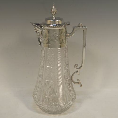 A very pretty Antique Victorian Silver Plated and hand-cut crystal claret jug, having a hand-engraved mount with scroll decoration, a Bacchus face on the spout, a hinged domed lid with a bead border and cast finial, a scrolled cast handle, a round hand-cut crystal body with tapering sides and a hobnail fluted panel pattern, all sitting on a flat star-cut base. Made by Mappin and Webb in there Princes Plate in ca. 1890. The dimensions of this fine hand-made antique silver-plated and crystal claret jug are height 28.5 cms (11.25 inches), length 14 cms (5.5 inches), and diameter at base is 11.5 cms (4.5 inches)..
