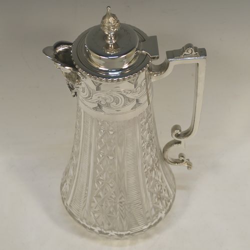 A very pretty Antique Victorian Silver Plated and hand-cut crystal claret jug, having a hand-engraved mount with scroll decoration, a Bacchus face on the spout, a hinged domed lid with a bead border and cast finial, a scrolled cast handle, a round hand-cut crystal body with tapering sides and a hobnail fluted panel pattern, all sitting on a flat star-cut base. Made by Mappin and Webb in there Princes Plate in ca. 1890. The dimensions of this fine hand-made antique silver-plated and crystal claret jug are height 28.5 cms (11.25 inches), length 14 cms (5.5 inches), and diameter at base is 11.5 cms (4.5 inches)..