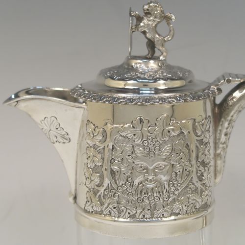 A very handsome Antique Victorian Sterling Silver and hand-cut crystal claret jug, having an ornate Bacchus style round mount with hand-chased grapevine work, a tendril style sided handle with a security ring, a hinged lid with a cast rampant lion and shield finial, together with a hand-cut crystal round body with straight sides and a tucked under belly above a flat star-cut base. This beautiful antique silver claret jug was made by Charles Boyton of London in 1889. The dimensions of this fine hand-made antique silver and crystal claret jug are height 27 cms (10.5 inches), and length 18.5 cms (7.5 inches).