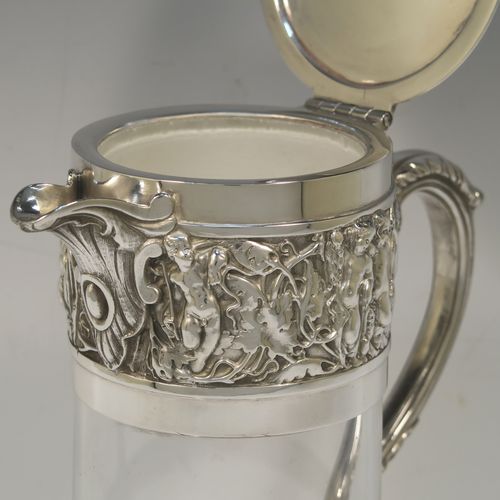 A very handsome Antique Victorian Silver Plated and hand-cut crystal claret jug, having an ornate Bacchus style round mount with hand-chased figural work, a cast side handle with a plain round security ring, a hinged lid with a cast rampant lion and shield finial, together with a hand-cut crystal round body with straight sides and a tucked under belly above a flat star-cut base. Made by Hukin and Heath of Sheffield in ca. 1880. The dimensions of this fine hand-made antique silver-plated and crystal claret jug are height 26 cms (10.25 inches), and length 16 cms (6.3 inches).